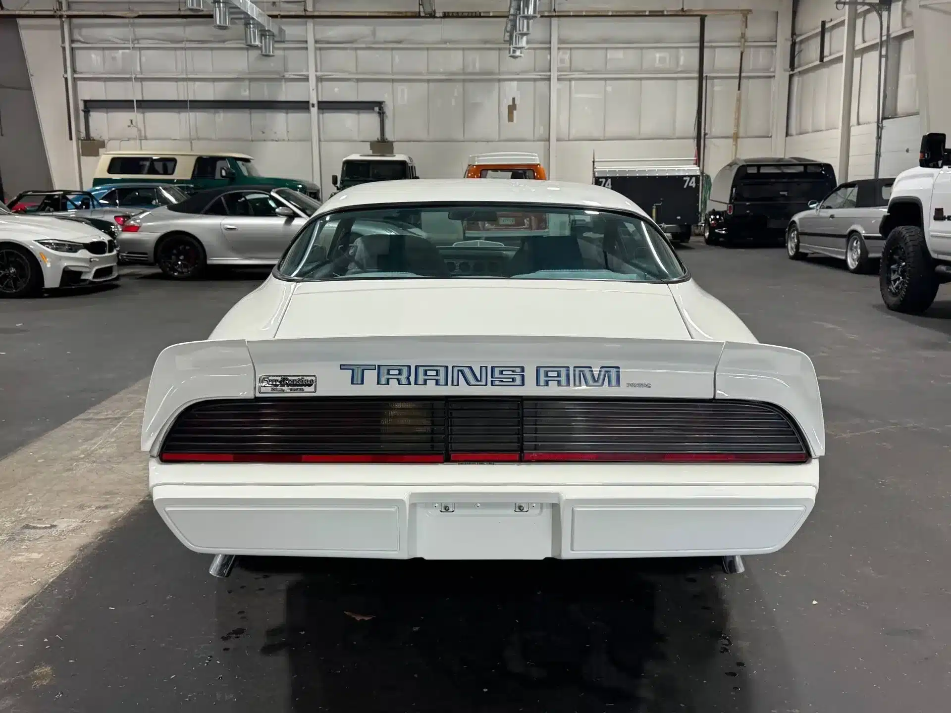 Weißer Pontiac Firebird Trans Am 1979, Heckansicht mit Schriftzug, in einer Fahrzeughalle.