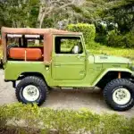 Toyota Land Cruiser von 1978 in Grün mit Softtop, klassische Geländewagen-Optik, auf einem Außengelände geparkt.