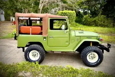 Toyota Land Cruiser von 1978 in Grün mit Softtop, klassische Geländewagen-Optik, auf einem Außengelände geparkt.