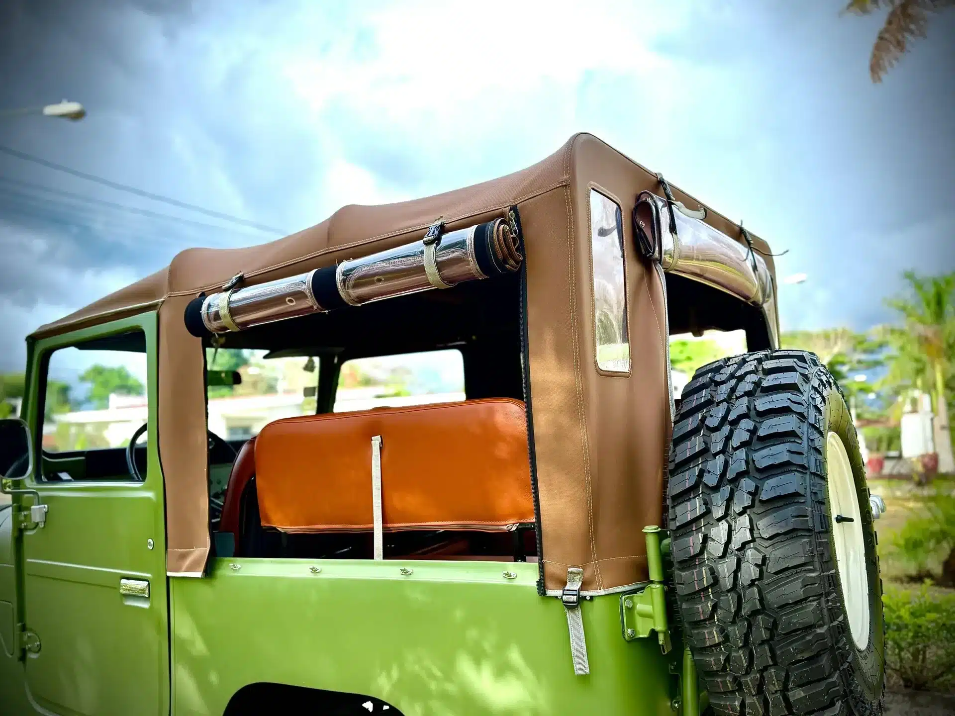 Detailansicht Toyota Land Cruiser 1978 FJ40 mit beigem Softtop und Ersatzrad, Fokus auf das Heck des Geländewagens, aufgenommen im Freien