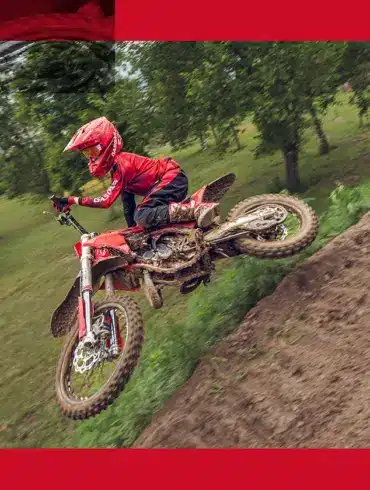 GasGas MC 85 19/16 2026 Motocross-Motorrad mit jungem Fahrer beim Sprung auf einer schlammigen Offroad-Strecke.