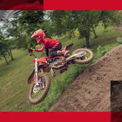 GasGas MC 85 19/16 2026 Motocross-Motorrad mit jungem Fahrer beim Sprung auf einer schlammigen Offroad-Strecke.