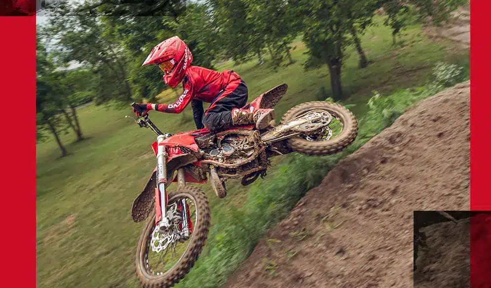 GasGas MC 85 19/16 2026 Motocross-Motorrad mit jungem Fahrer beim Sprung auf einer schlammigen Offroad-Strecke.