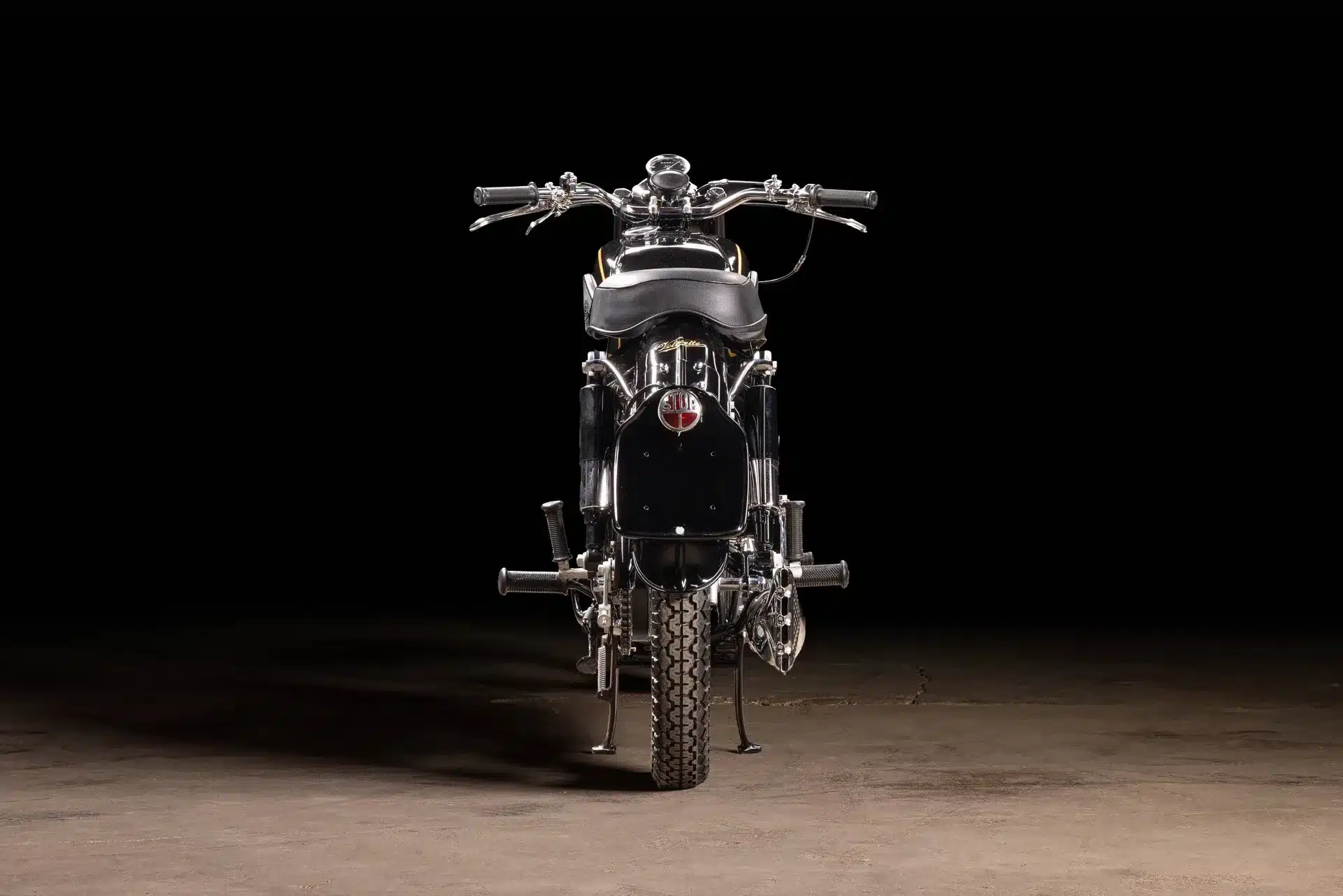 Restaurierte Velocette MAC 350 von 1953 als Rückansicht, auf dunklem Hintergrund fotografiert.