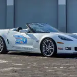 Weiße Chevrolet Corvette 427 Convertible Collector Edition 60th Anniversary Indianapolis 500 Pace Car von 2013, Seitenansicht vor einer Garage.