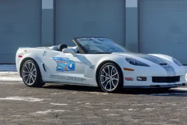 Weiße Chevrolet Corvette 427 Convertible Collector Edition 60th Anniversary Indianapolis 500 Pace Car von 2013, Seitenansicht vor einer Garage.