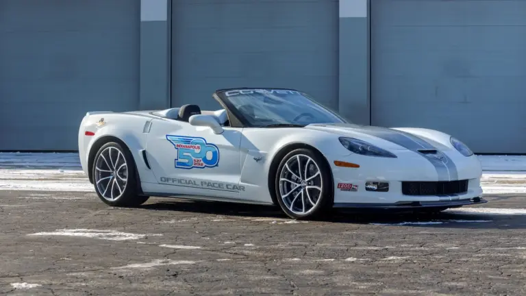 Weiße Chevrolet Corvette 427 Convertible Collector Edition 60th Anniversary Indianapolis 500 Pace Car von 2013, Seitenansicht vor einer Garage.