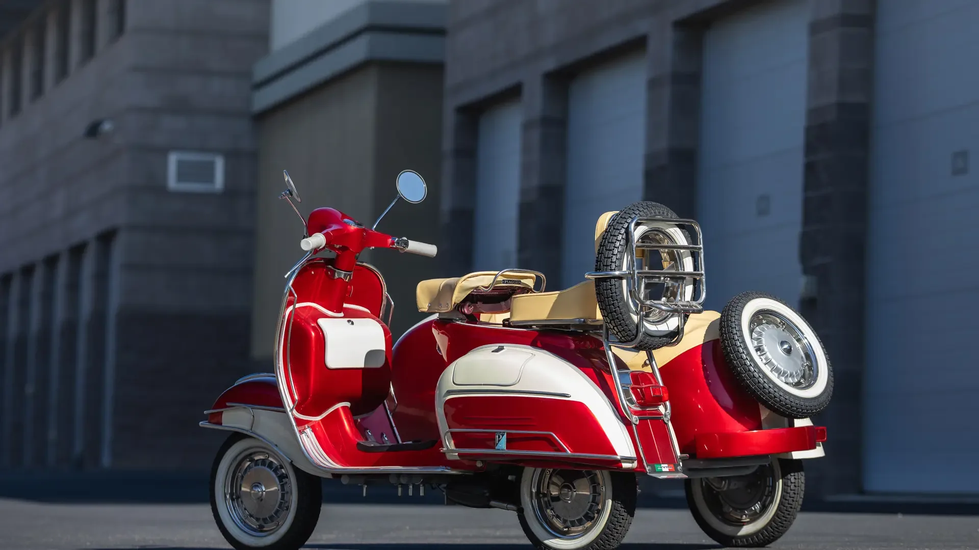Restaurierte Piaggio Vespa 150 Super von 1966 mit Beiwagen in Rot und Weiß vor moderner Gebäude-Kulisse