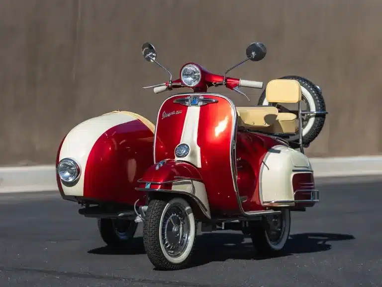 Restaurierte Piaggio Vespa 150 Super von 1966 mit Beiwagen in Zweifarblackierung auf einer Straße