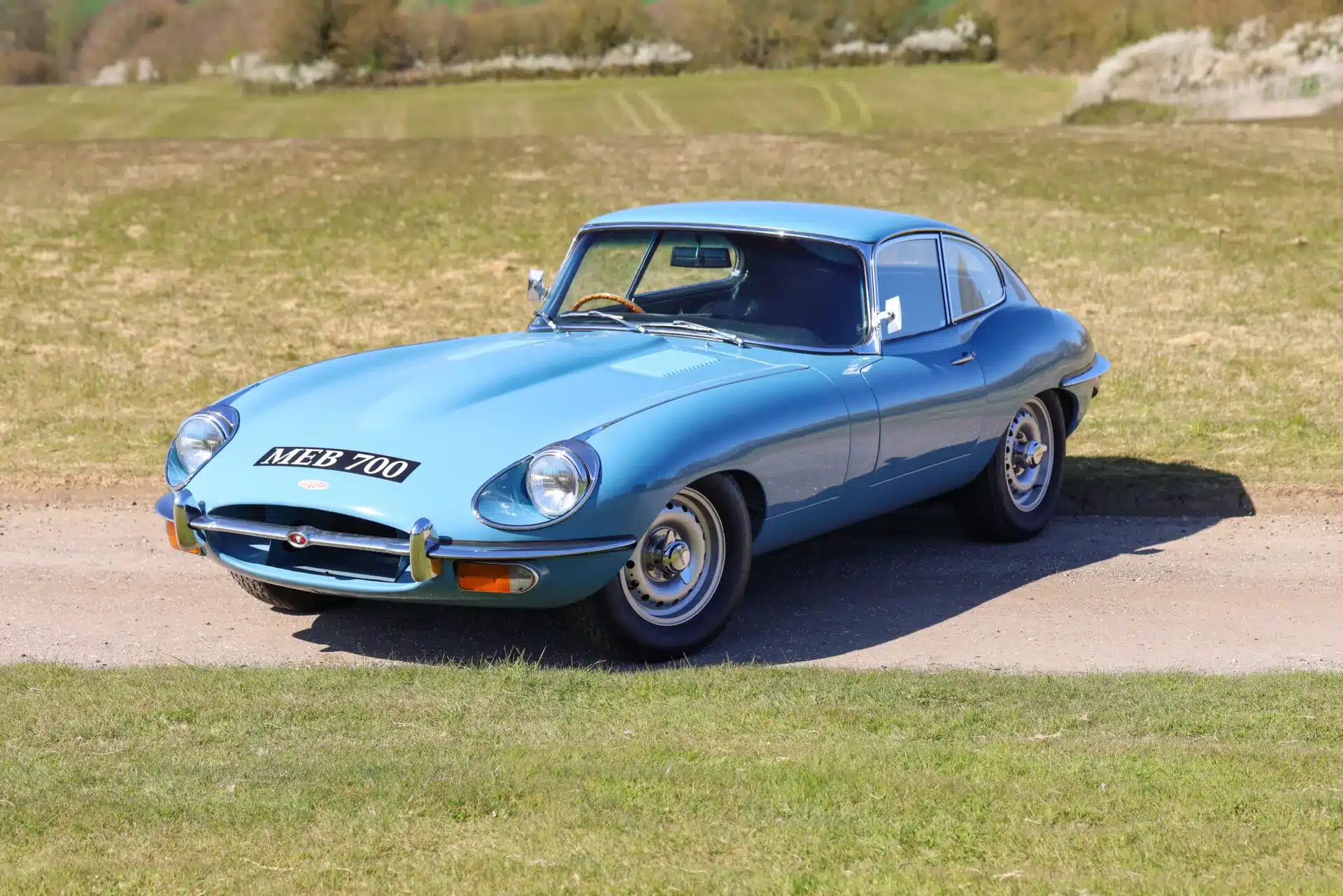 Jaguar E-Type 4.2 Series 2 Fixed Head Coupé von 1969 in originaler Light Blue Lackierung auf einer Landstraße.