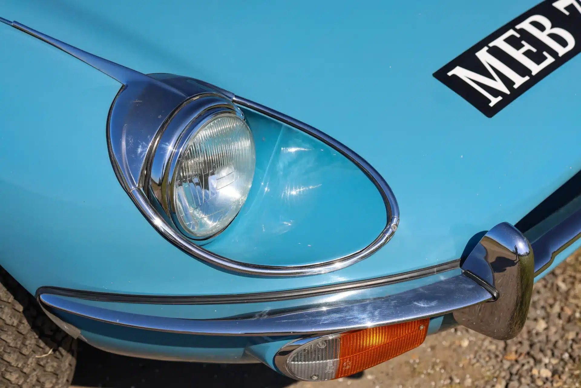 Nahaufnahme des vorderen linken Scheinwerfers, Blinkers und Stoßfängers eines hellblauen Jaguar E-Type 4.2 Series 2