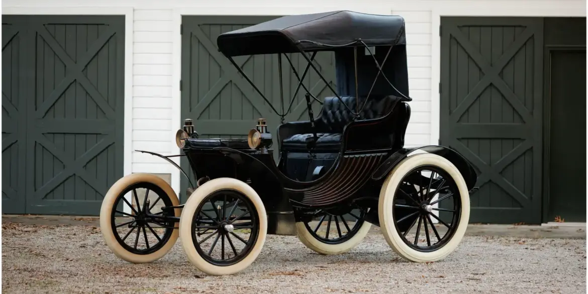 Duryea Four Wheel Phaeton von 1905 mit offener Karosserie und weißen Reifen vor Toren