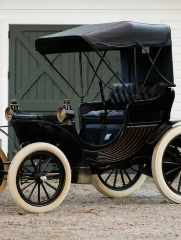 Duryea Four Wheel Phaeton von 1905 mit offener Karosserie und weißen Reifen vor Toren