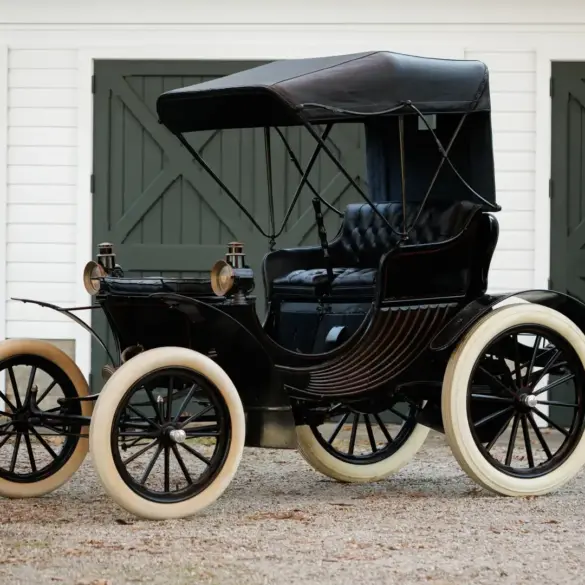 Duryea Four Wheel Phaeton von 1905 mit offener Karosserie und weißen Reifen vor Toren