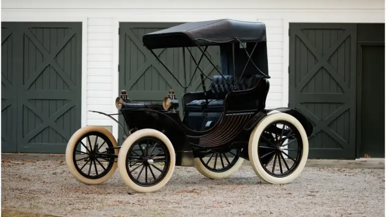 Duryea Four Wheel Phaeton von 1905 mit offener Karosserie und weißen Reifen vor Toren
