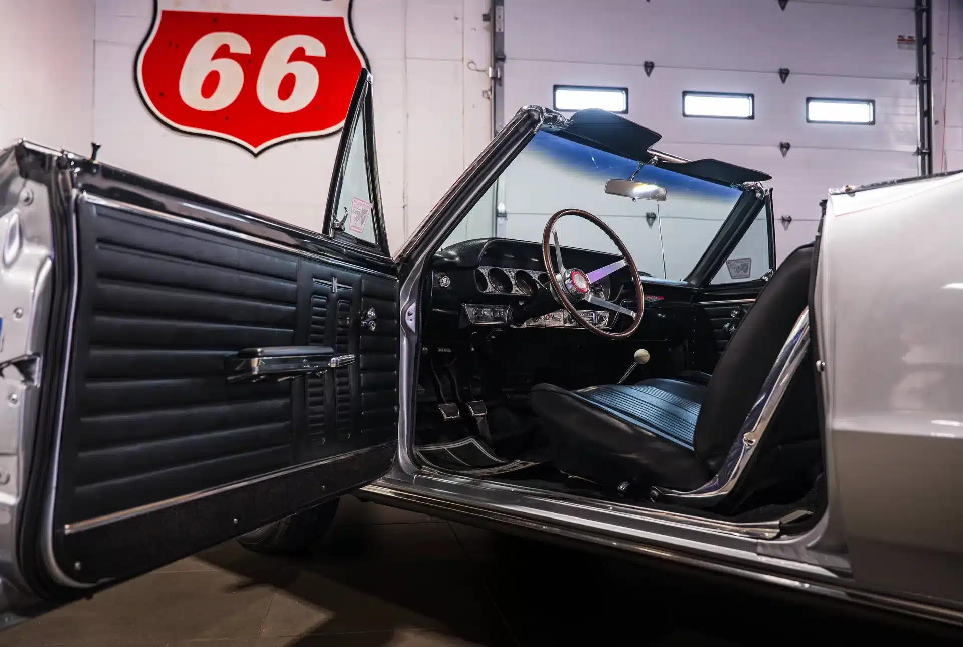 Detailaufnahme des Innenraums eines Pontiac GTO von 1964 mit offener Tür, Lenkrad und Armaturenbrett.