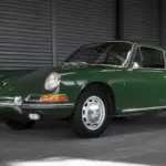 Ein grüner Porsche 911 Coupé aus dem Baujahr 1966 in unrestauriertem Originalzustand, seitlich in einer Halle fotografiert.