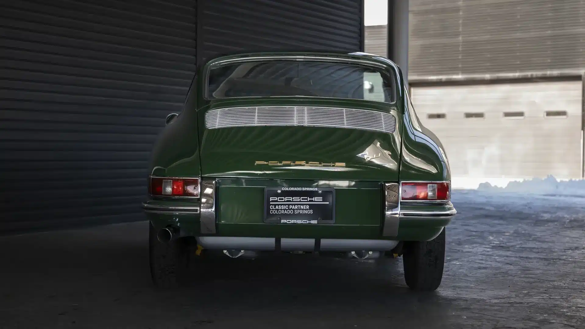Das Bild zeigt das Heck eines Porsche 911 Coupé Baujahr 1966 in Irish Green, aufgenommen in einer Halle.