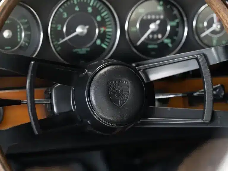 Innenansicht des Lenkrads und Armaturenbretts eines Porsche 911 Coupé von 1966, mit originalen Rundinstrumenten und Holzapplikationen.