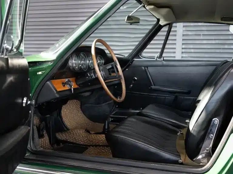 Blick auf den originalen Innenraum eines Porsche 911 Coupé von 1966 mit Holzlenkrad und schwarzem Kunstleder.