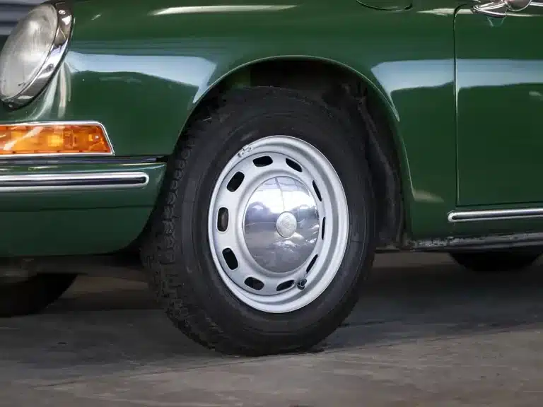Vorderer Radbereich eines grünen Porsche 911 Coupé von 1966 mit originaler Felge.