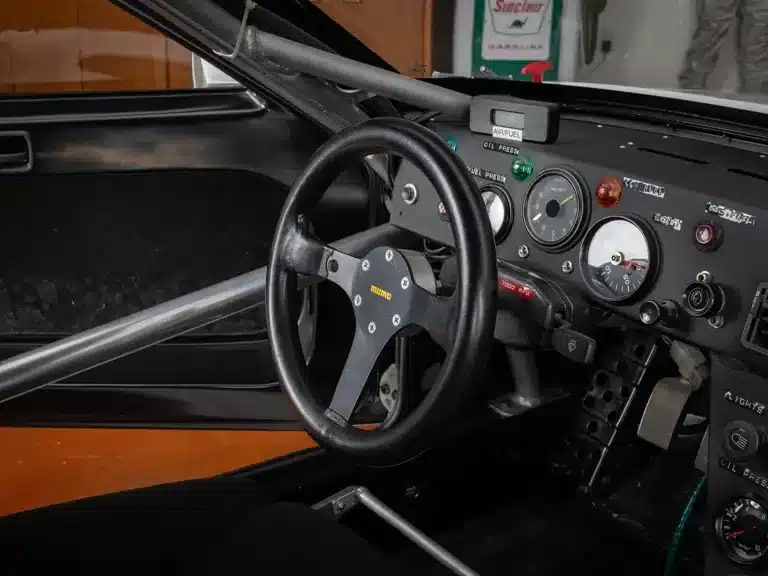 Innenraum des Porsche 924 GTP mit Momo-Lenkrad, Überrollkäfig und Armaturenbrett mit Rennsportinstrumenten.