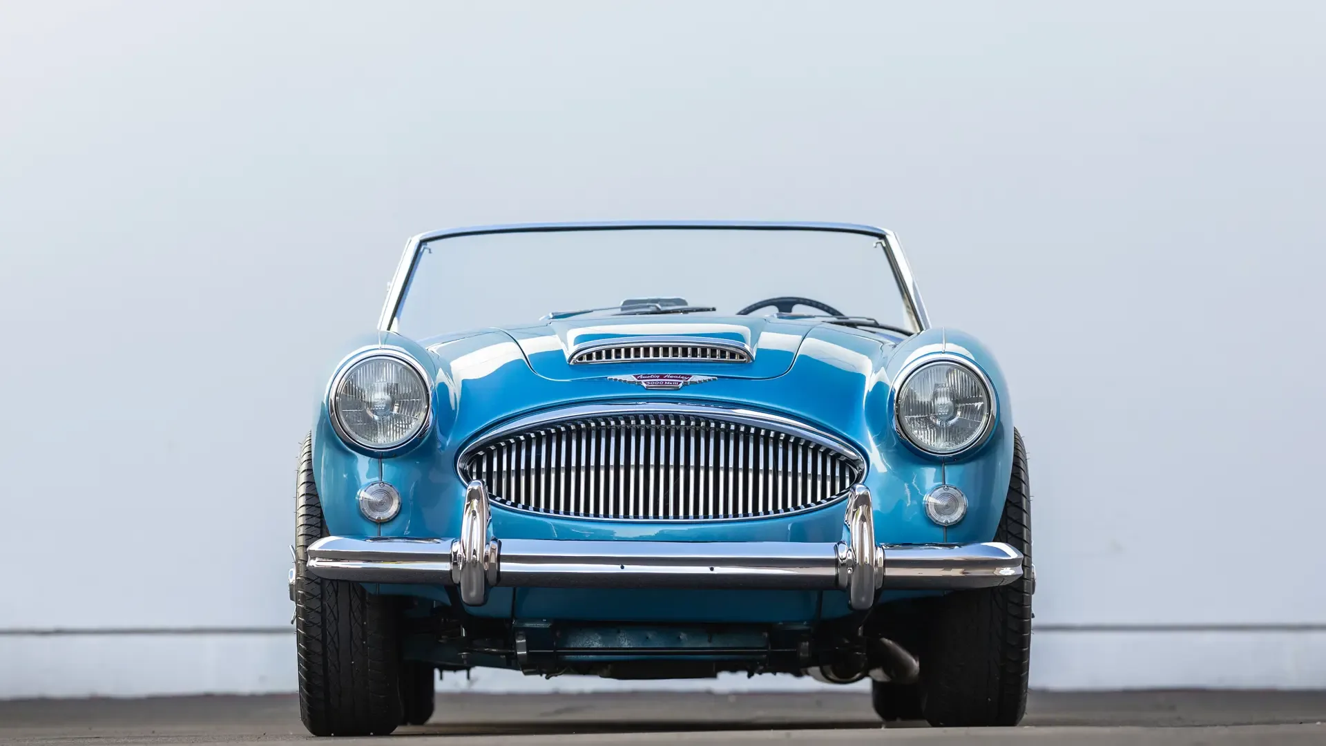 Frontansicht eines blauen Austin-Healey 3000 Mk III BJ8 Roadsters, Baujahr 1965, vor neutralem Hintergrund