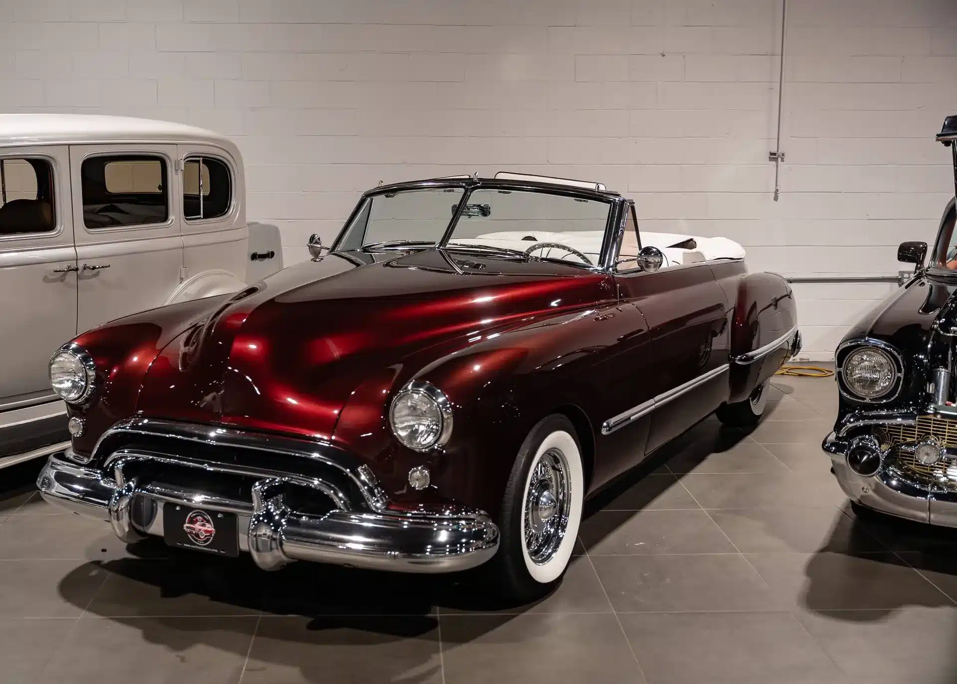 Burgunderrotes Oldsmobile 88 Convertible von 1948 mit weißer Innenausstattung in einer Ausstellungshalle.