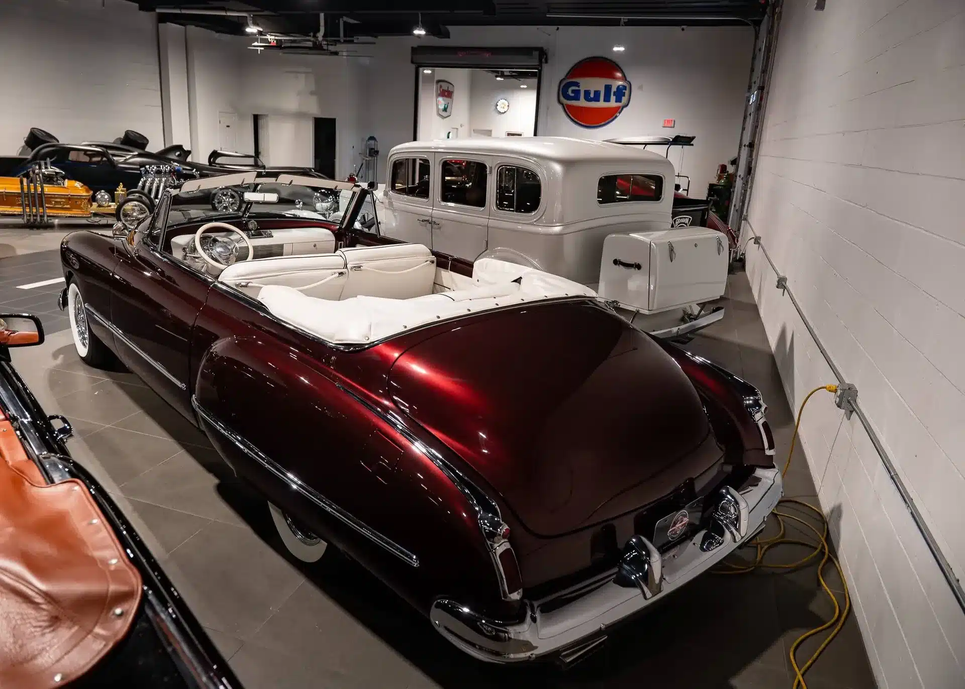 Burgunderrotes Oldsmobile 88 Convertible von 1948 mit weißem Lederausstattung, fotografiert in einer Oldtimer-Ausstellung.