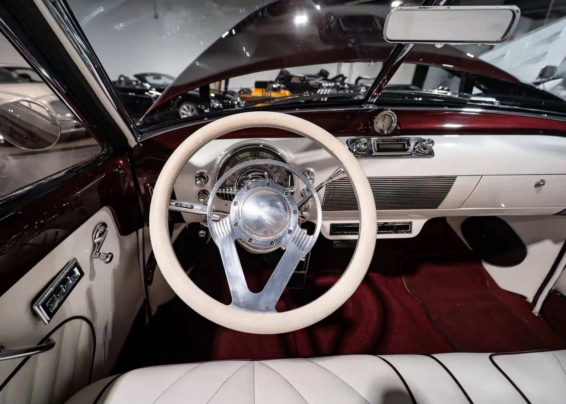 Innenraum eines Oldsmobile 88 Convertible von 1948 mit weißem Leder, burgunderrotem Armaturenbrett und klassischem Lenkrad.