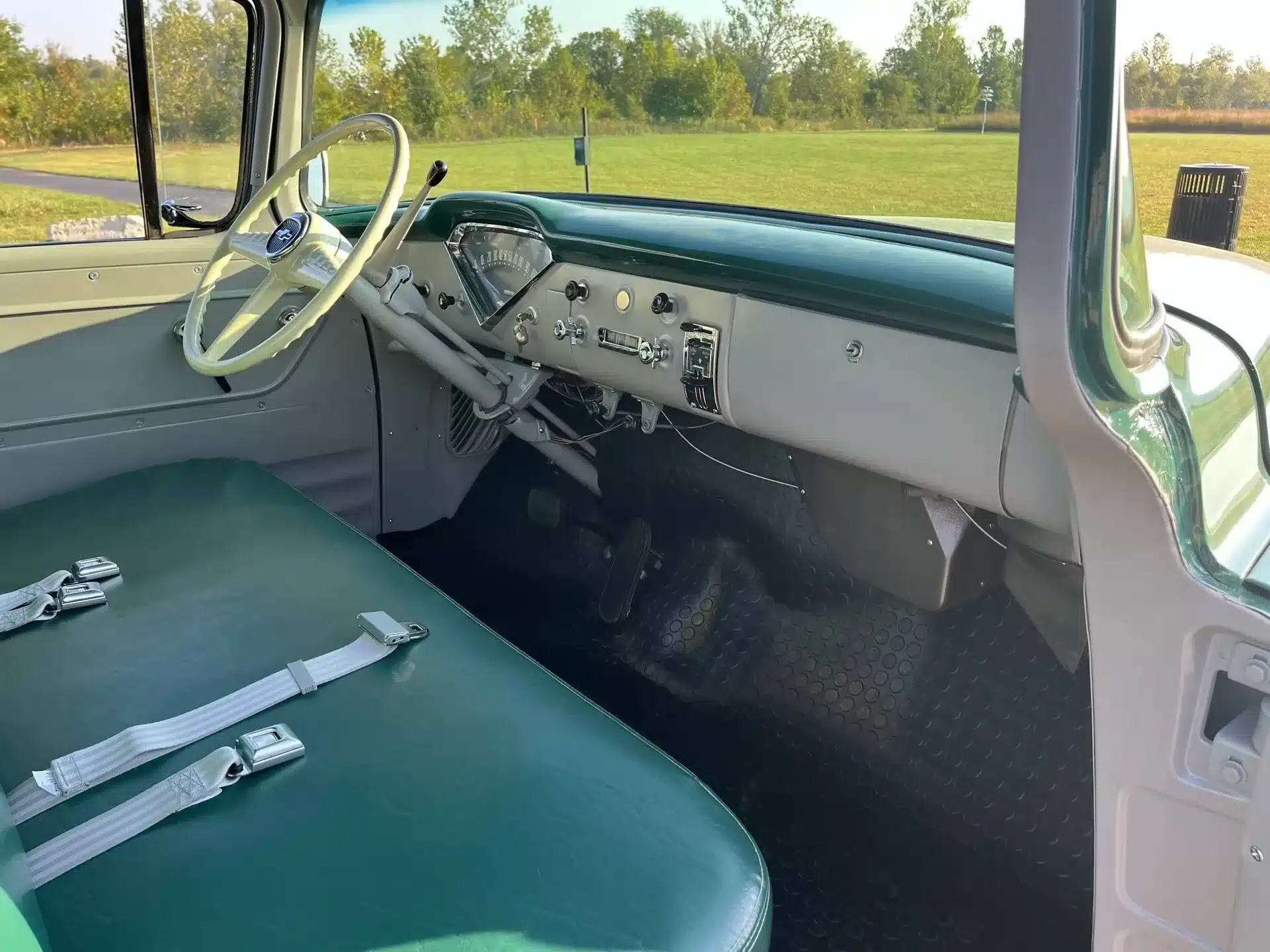 Blick in den Innenraum eines zweifarbig lackierten Chevrolet 3100 von 1956 mit grün-ivoryfarbener Sitzbank und klassischem Lenkrad.