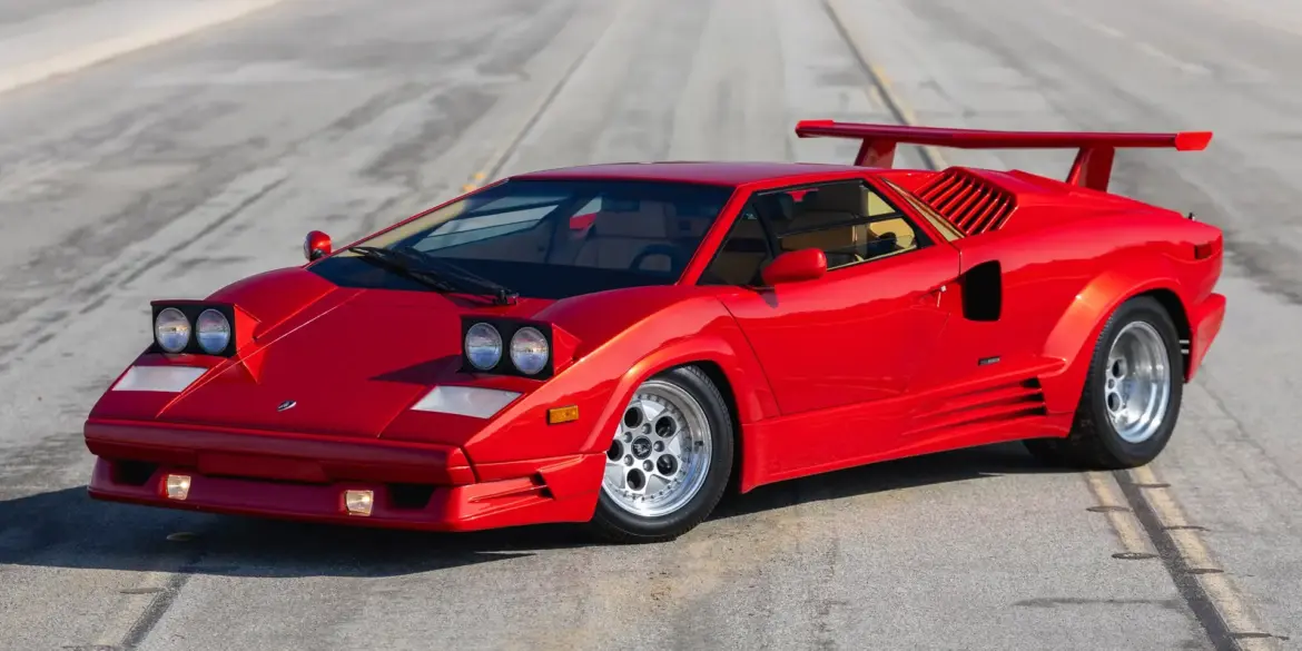 Roter Lamborghini Countach 25th Anniversary Edition, Baujahr 1989, mit geöffneten Scheinwerfern und markantem Heckflügel auf leerer Straße