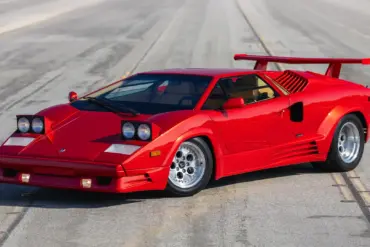 Roter Lamborghini Countach 25th Anniversary Edition, Baujahr 1989, mit geöffneten Scheinwerfern und markantem Heckflügel auf leerer Straße