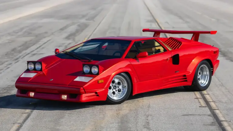 Roter Lamborghini Countach 25th Anniversary Edition, Baujahr 1989, mit geöffneten Scheinwerfern und markantem Heckflügel auf leerer Straße