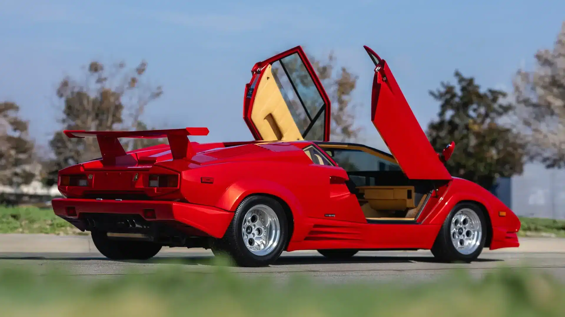 Roter Lamborghini Countach 25th Anniversary Edition aus dem Jahr 1989 mit geöffneten Scherentüren, Seiten- und Heckansicht.