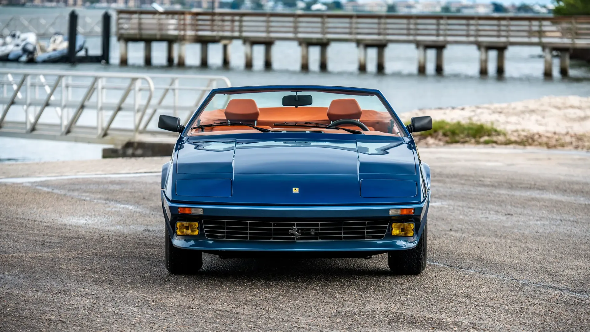 Ferrari 365 GTB/4 Daytona NART Spider by Michelotti in Dunkelblau und Grau mit orangem Lederinterieur, Frontansicht vor maritimer Kulisse.