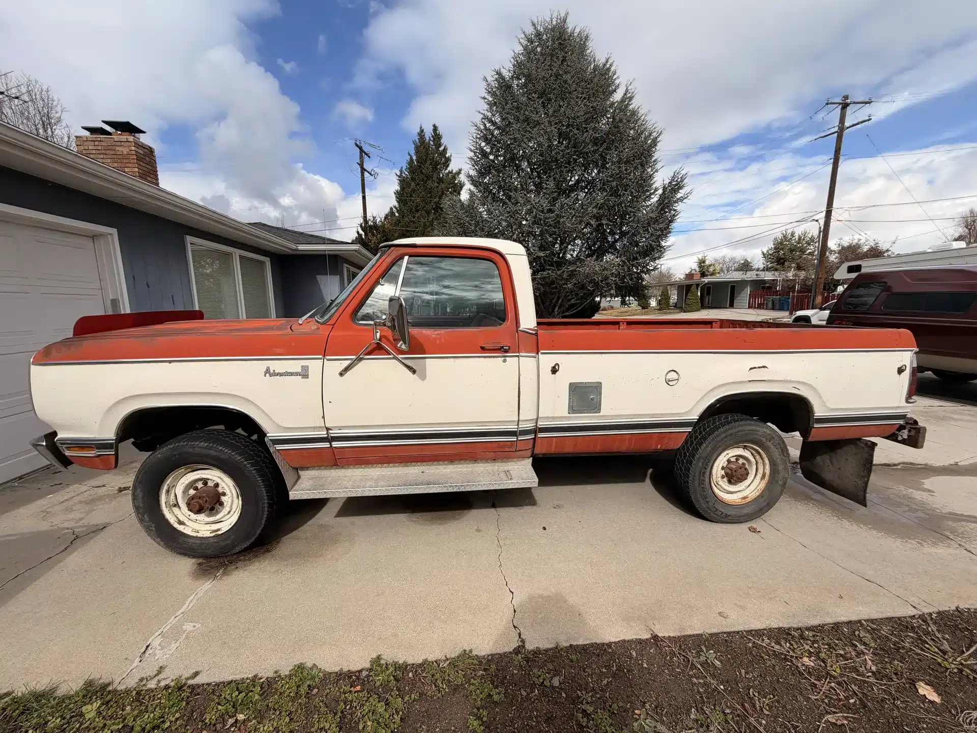 Dodge 200 aus dem Jahr 1978 in weiß-orange, seitlich fotografiert auf einer Einfahrt.