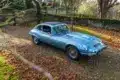 Jaguar E-Type Serie 1 4.2 Fixed Head Coupé 1965 in Opalescent Silver Blue, geparkt im Freien auf einem mit Laub bedeckten Kiesweg.