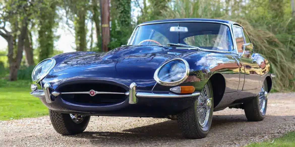 Jaguar E-Type Series 1 4.2 Fixed Head Coupé, Baujahr 1965, in Indigo Blue, auf einer Auffahrt im Grünen