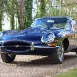 Jaguar E-Type Series 1 4.2 Fixed Head Coupé, Baujahr 1965, in Indigo Blue, auf einer Auffahrt im Grünen