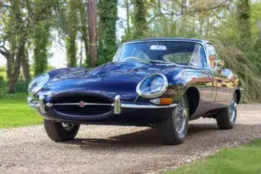 Jaguar E-Type Series 1 4.2 Fixed Head Coupé, Baujahr 1965, in Indigo Blue, auf einer Auffahrt im Grünen