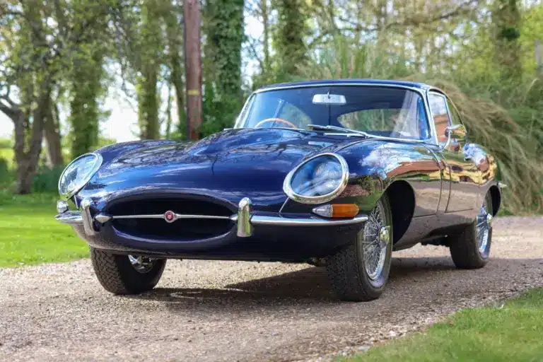 Jaguar E-Type Series 1 4.2 Fixed Head Coupé, Baujahr 1965, in Indigo Blue, auf einer Auffahrt im Grünen