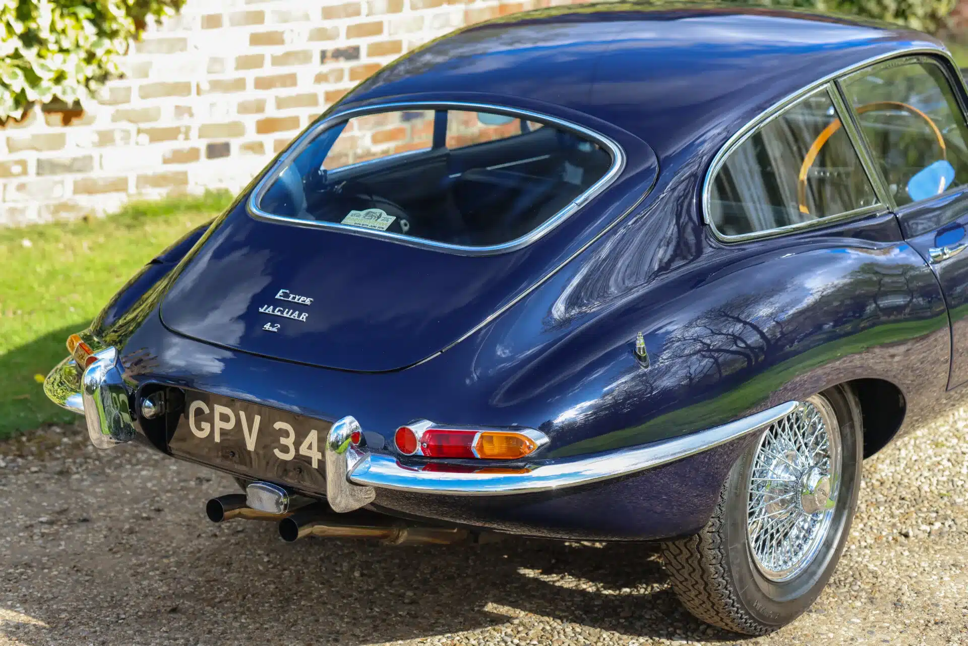 Jaguar E-Type Series 1 4.2 Fixed Head Coupé von 1965 in Indigo Blue, fotografiert von schräg hinten mit sichtbarem Kennzeichen