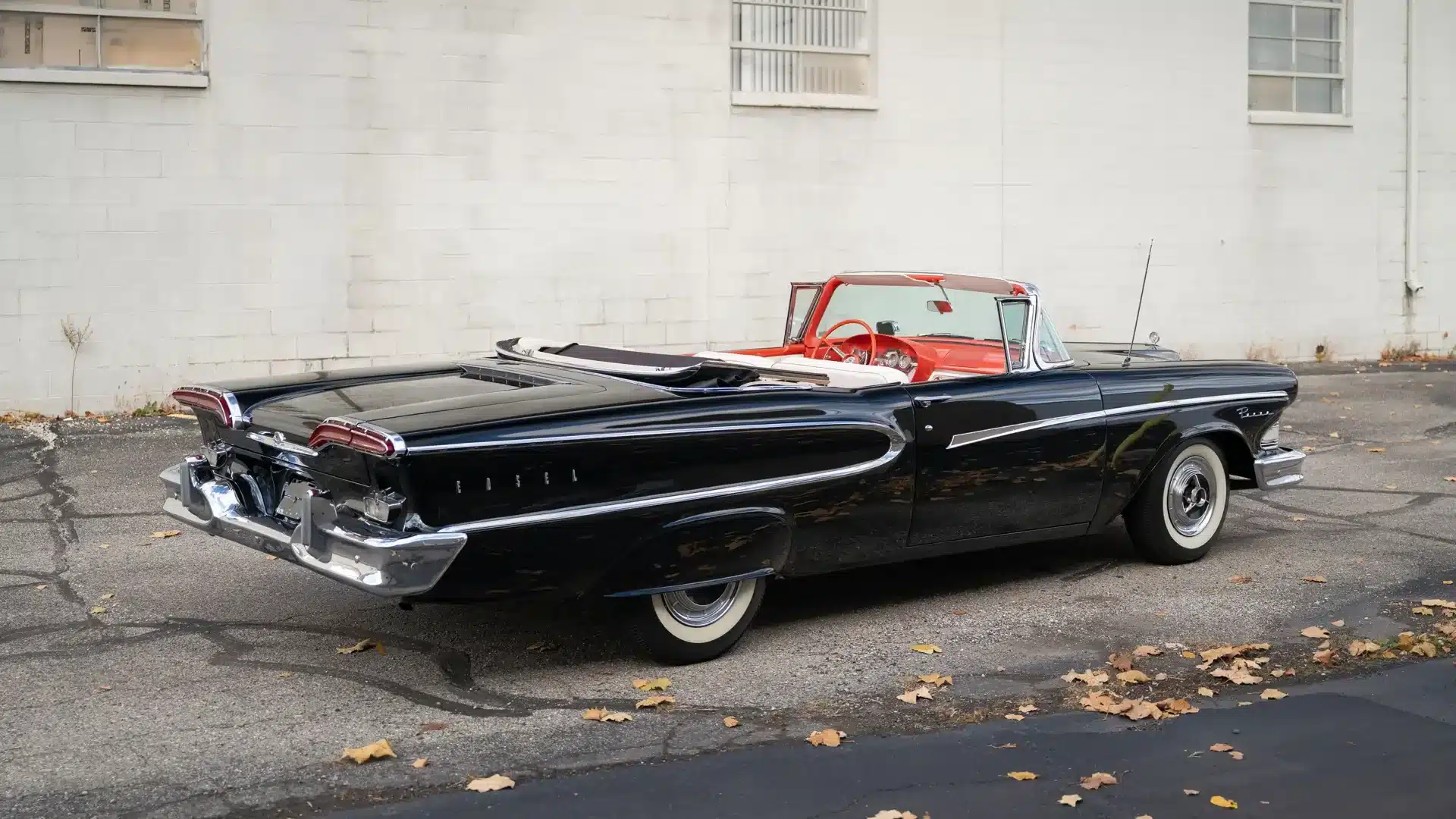 Schwarzer Edsel Pacer Convertible von 1958 mit roten und weißen Ledersitzen, geparkt vor einer weißen Wand