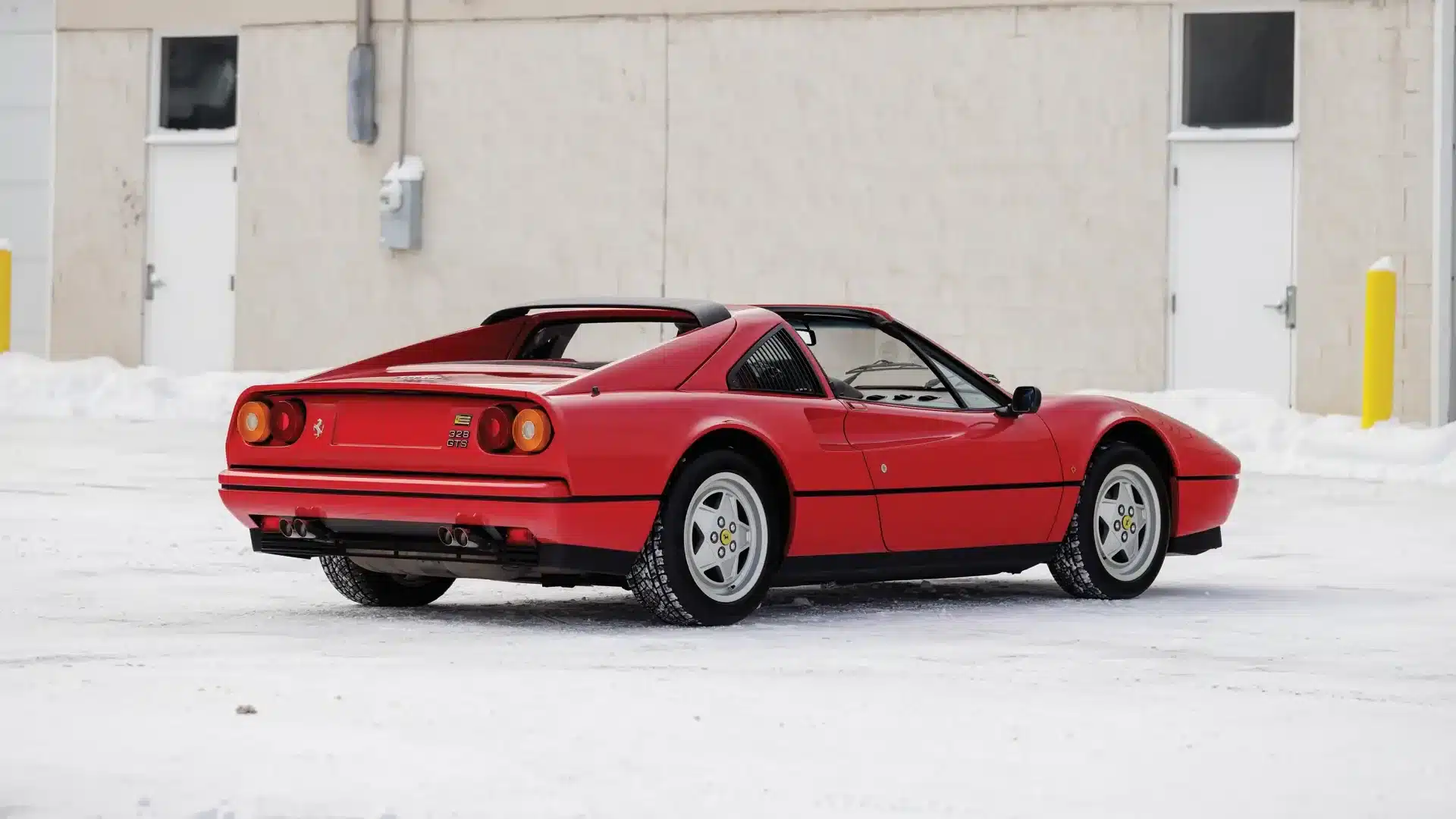 Heckansicht eines roten Ferrari 328 GTS Targa, Baujahr 1988, auf schneebedecktem Untergrund, mit abgenommenem Dachpaneel.