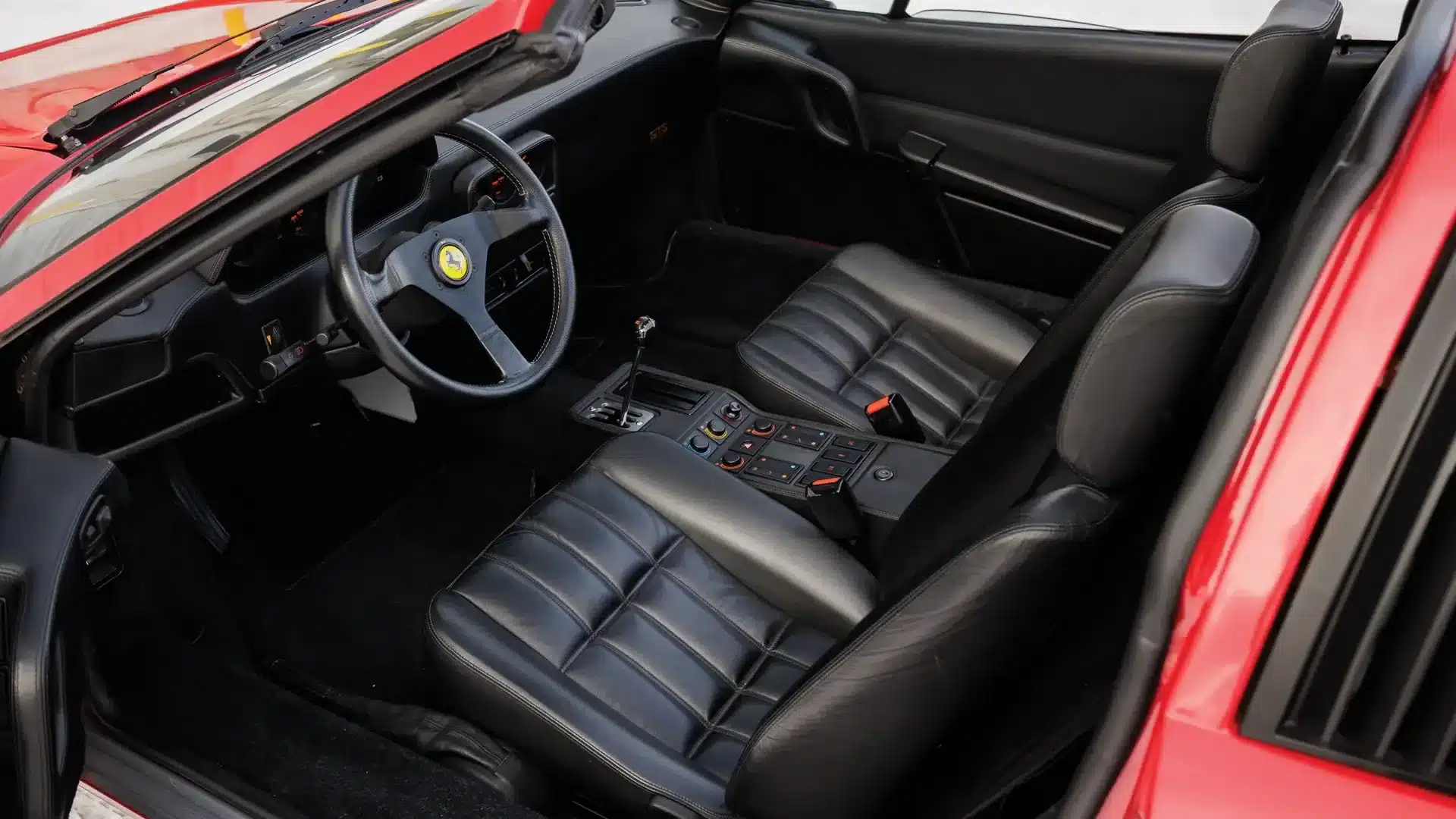 Innenraumansicht eines Ferrari 328 GTS von 1988 mit schwarzem Leder und typischem Sportwagen-Cockpit.