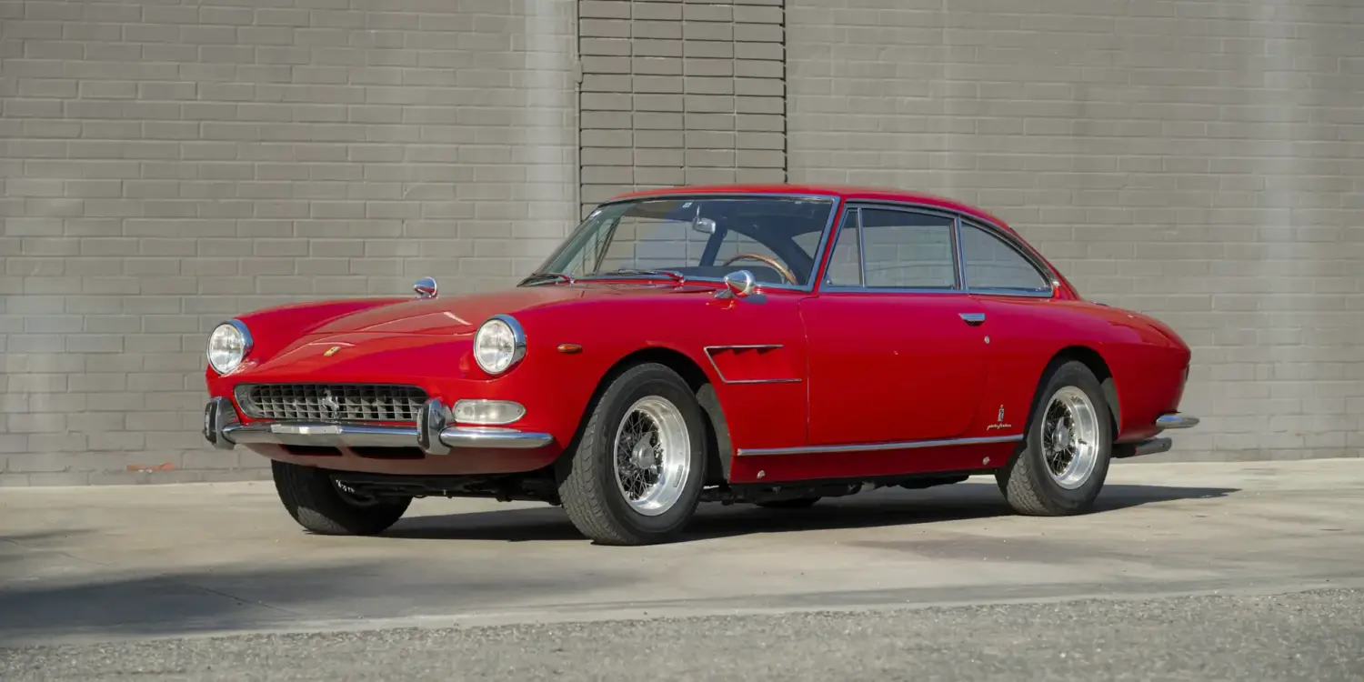 Ferrari 330 GT 2+2 Serie II Baujahr 1966 in Rot, Seitenansicht vor einer grauen Mauer, klassisches Coupé mit stilvollem Design.