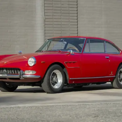 Ferrari 330 GT 2+2 Serie II Baujahr 1966 in Rot, Seitenansicht vor einer grauen Mauer, klassisches Coupé mit stilvollem Design.