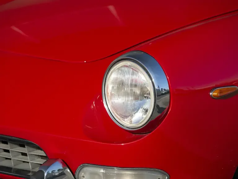 Roter Ferrari 330 GT 2+2, Nahaufnahme des Frontscheinwerfers mit verchromtem Rand