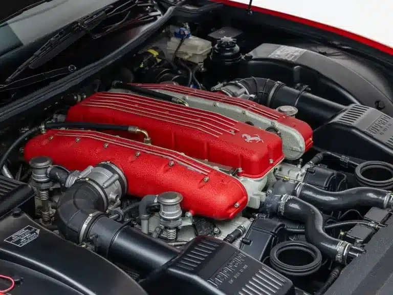 Motorraum eines Ferrari Superamerica mit rotem V12-Motor und technischen Details.